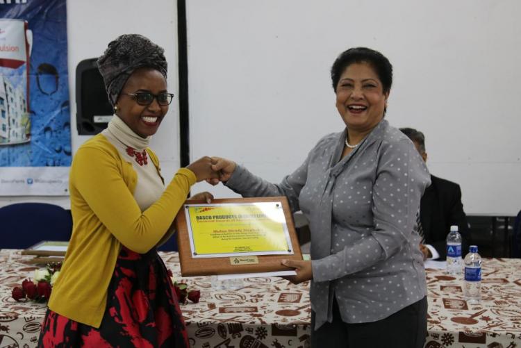 Ms. Wendy Stephanie Mutua of the School of Arts and Design receiving a  Duracoat Award of Academic Excellence  Certificate from Ms Zarina of Basco Paints