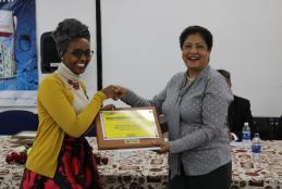 Ms. Wendy Stephanie Mutua of the School of Arts and Design receiving a  Duracoat Award of Academic Excellence  Certificate from Ms Zarina of Basco Paints